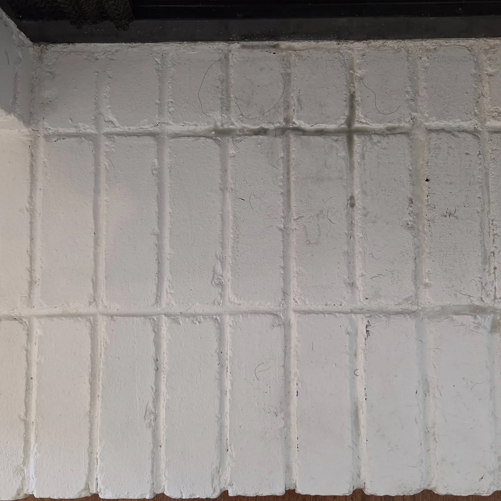 Hair and debris on painted fireplace brick before detailed cleaning