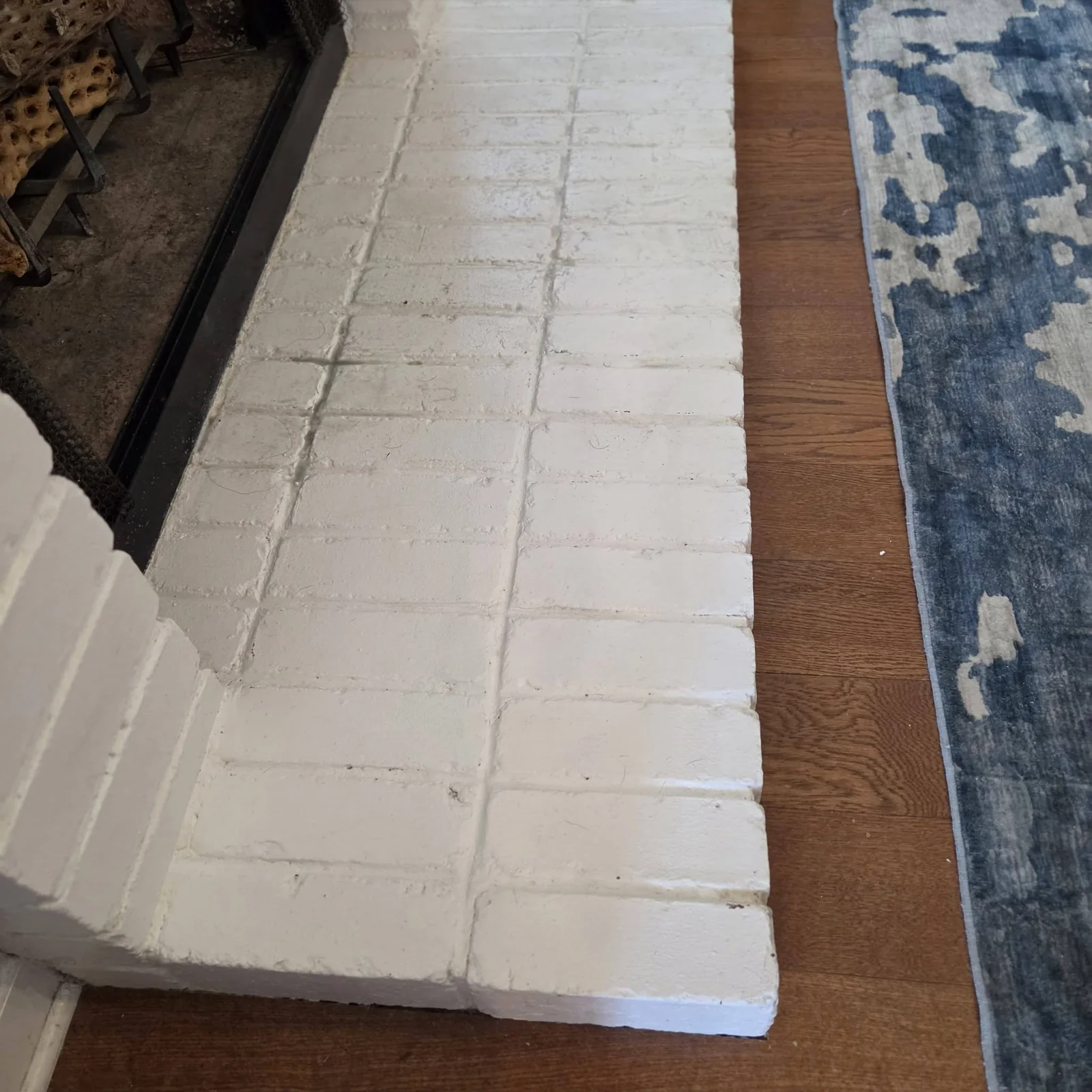 Painted brick hearth with buildup before careful cleaning