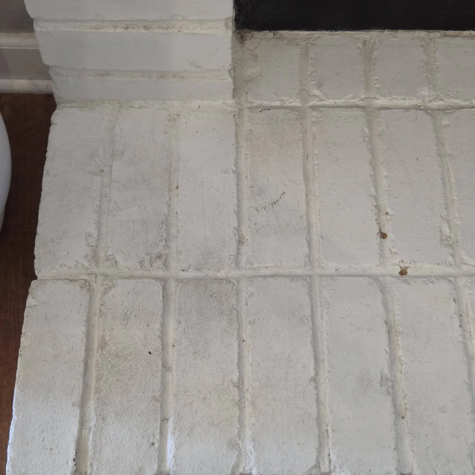 Close view of painted fireplace brick with dust and hair before cleaning